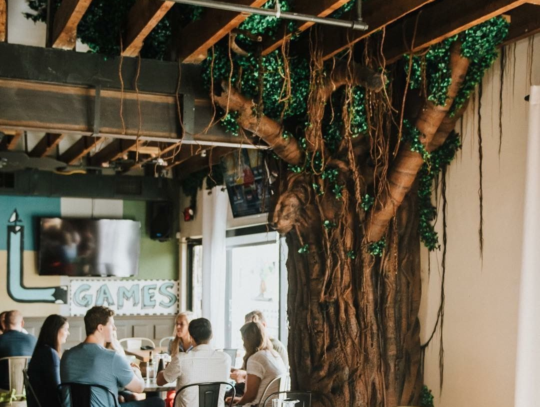 People seated at a table inside, near a large artificial tree. 