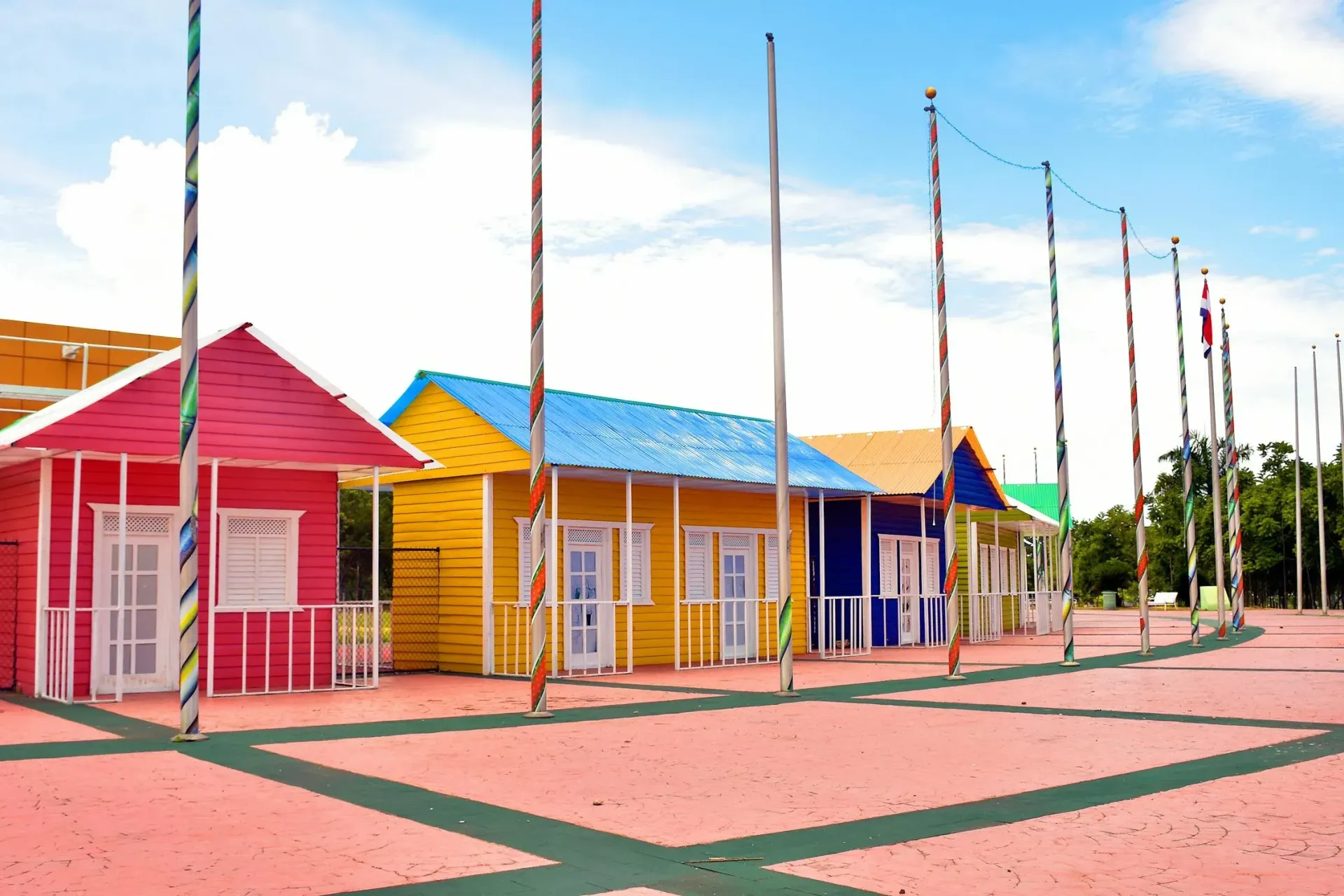 Colorful row of small houses with matching poles against a blue sky.