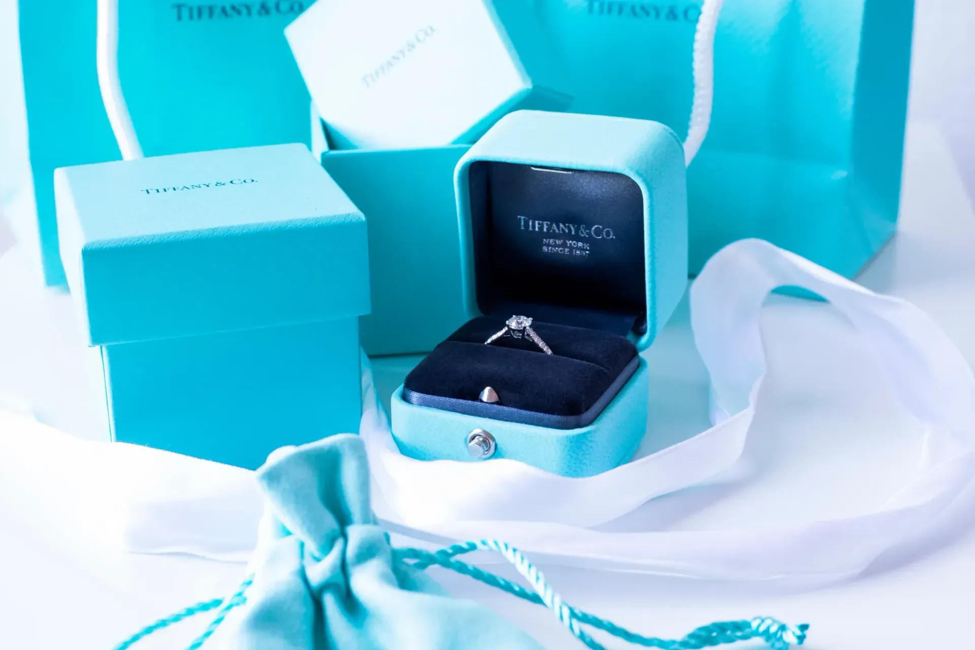 Tiffany & Co. engagement ring in signature blue box with gift bags and ribbon.