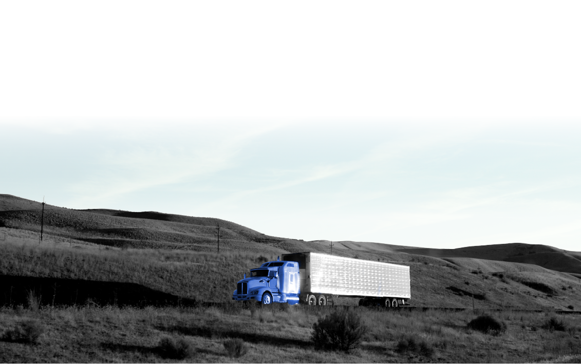 A blue semi truck is driving down a dirt road.
