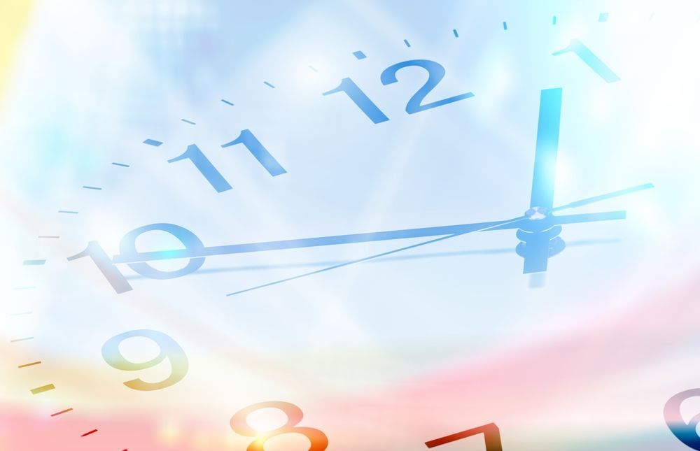Clock face, hands pointing near 10 o'clock. Soft, colorful, blurred background.