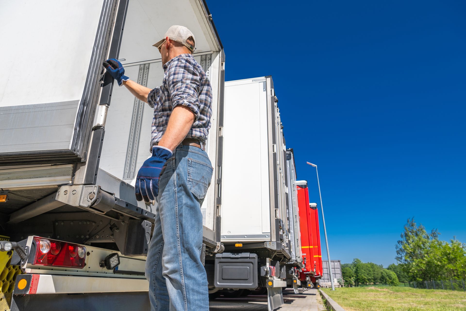 A man is standing on the back of a semi truck.