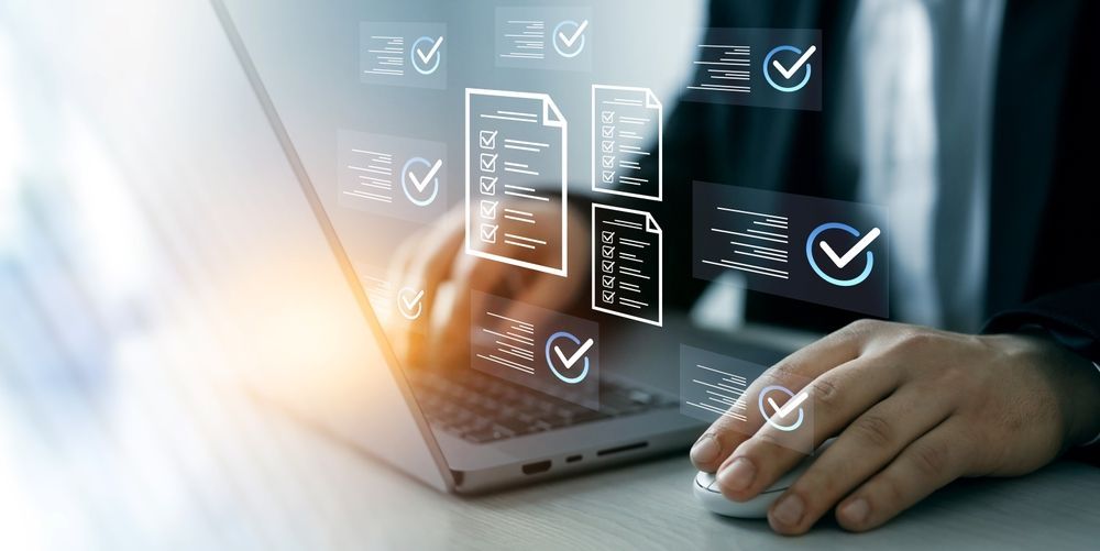 Person using a laptop, interacting with digital document icons and checkmarks; work setting.