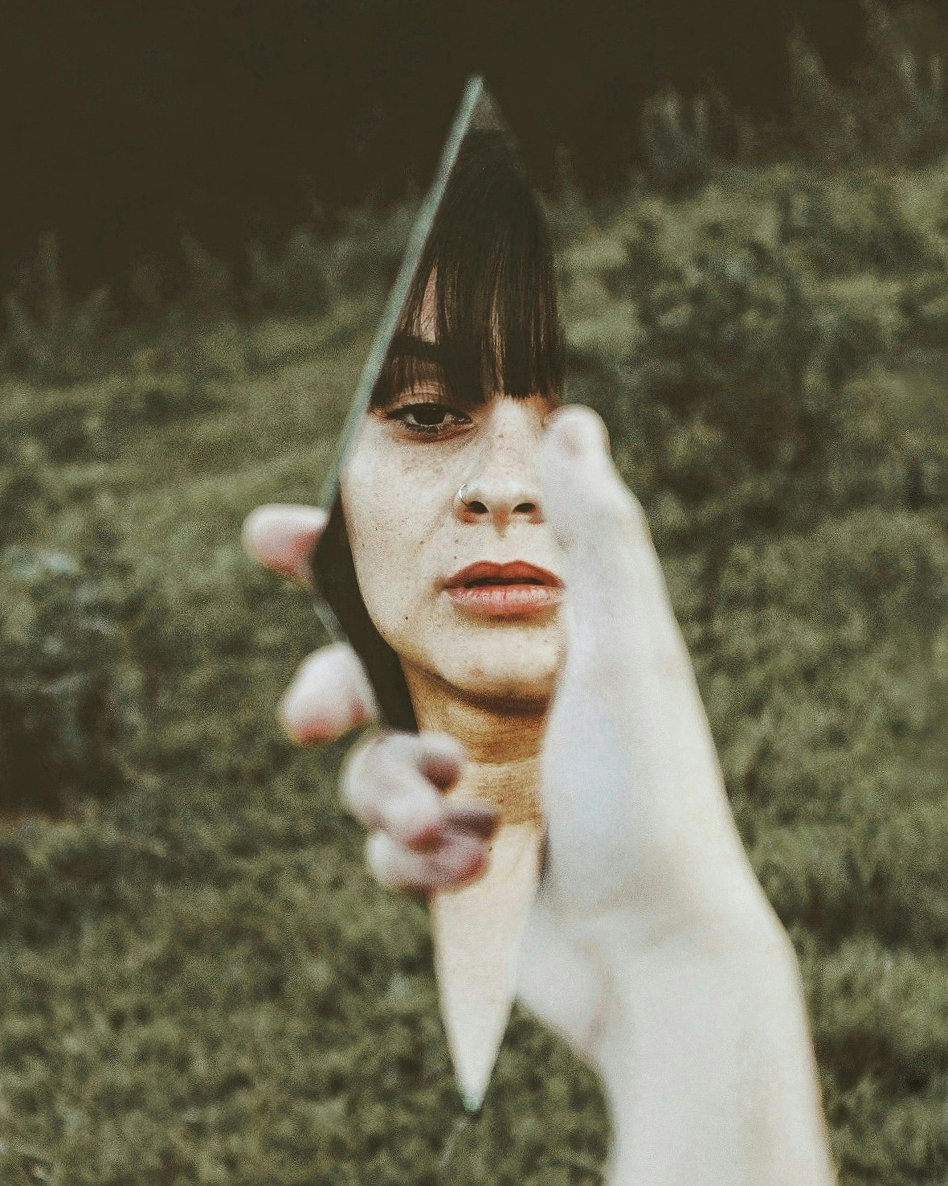 A woman is looking at her reflection in a broken mirror.