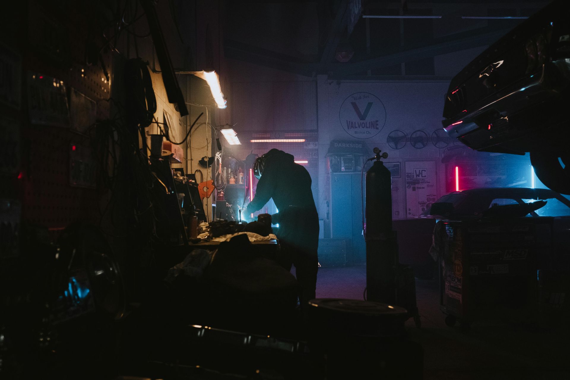 A man is welding a car in a dark garage