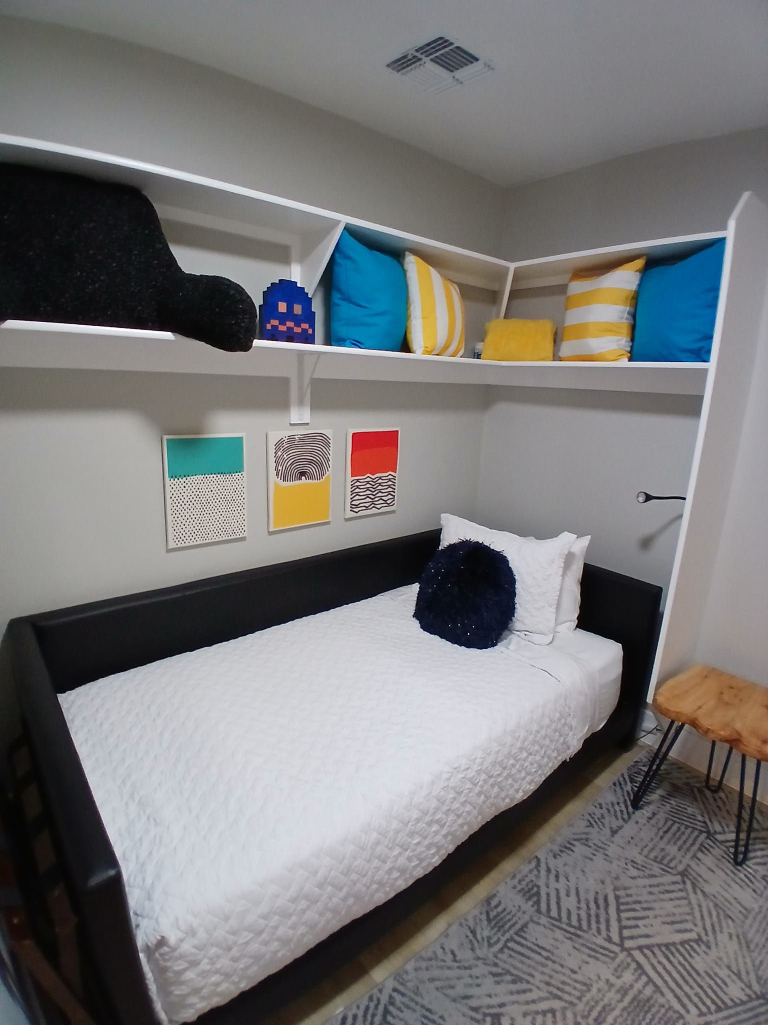 A bedroom with a bed and shelves with pillows on them