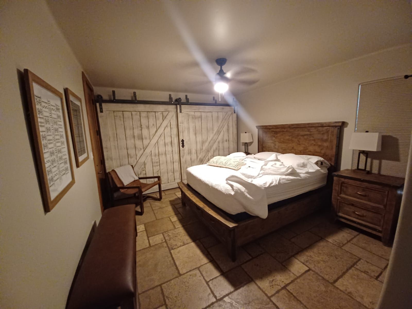 A bedroom with a bed , nightstand , chair and sliding barn doors.