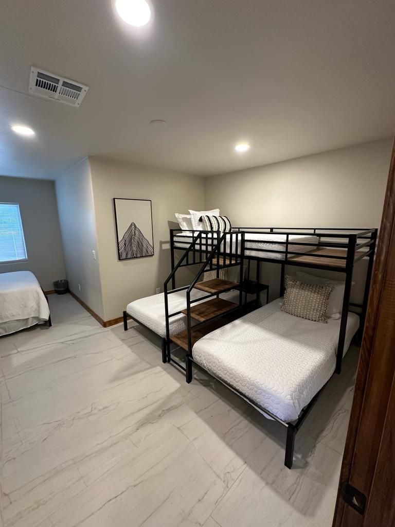 A bedroom with two beds and a bunk bed.