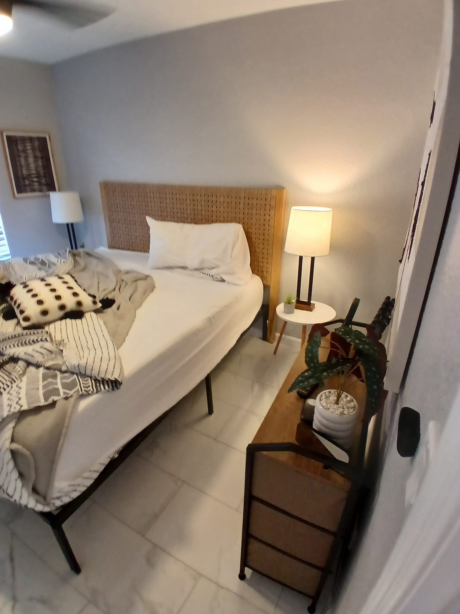 A bedroom with a bed , two lamps and a dresser