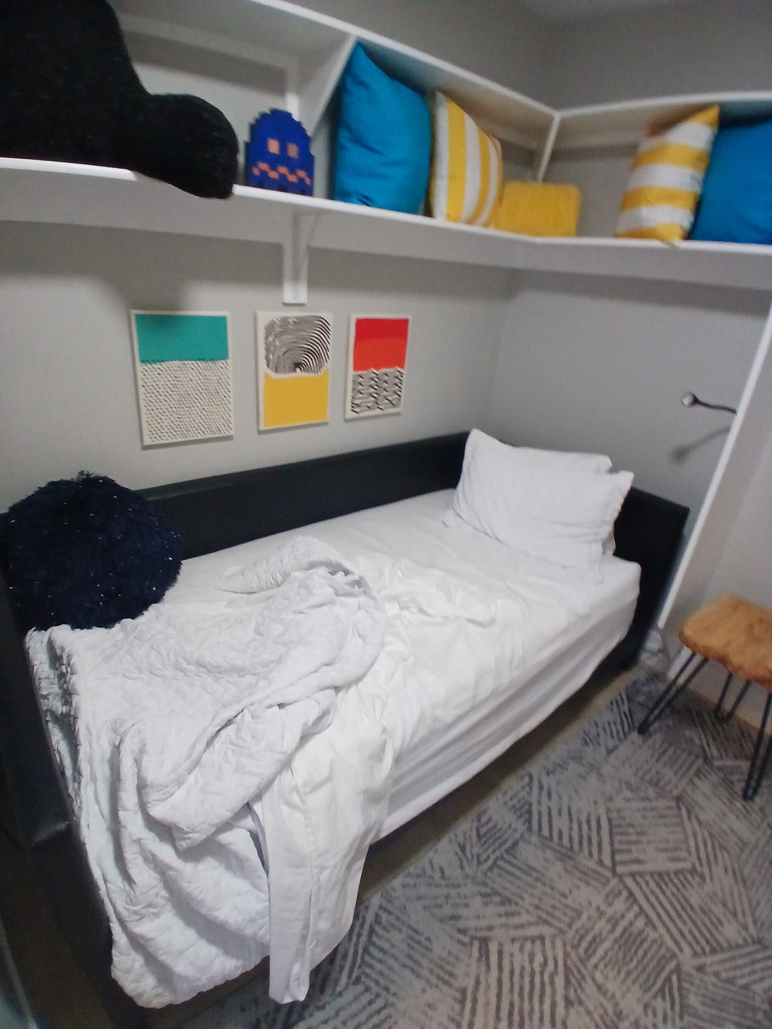 A bedroom with a bed and pillows on the shelves