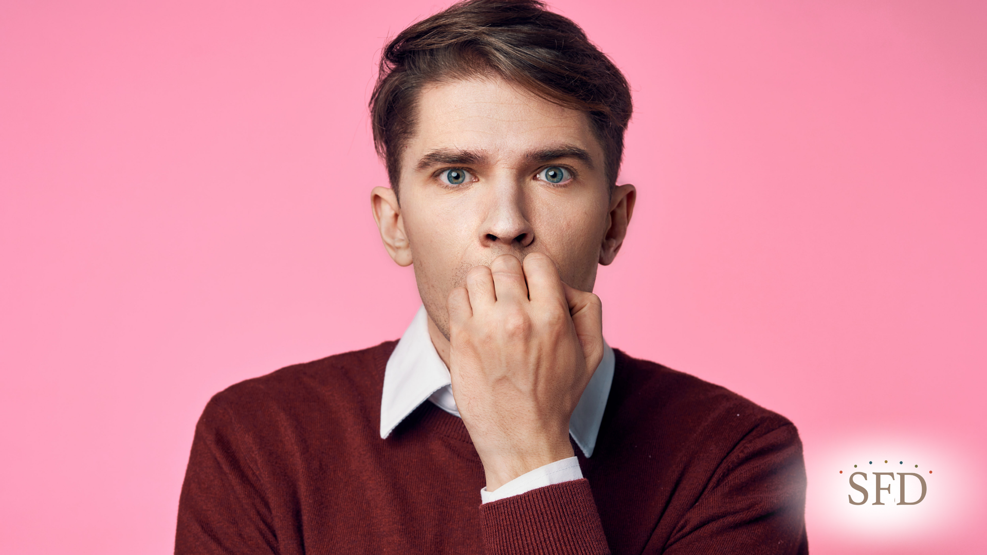A man is covering his mouth with his hand on a pink background.