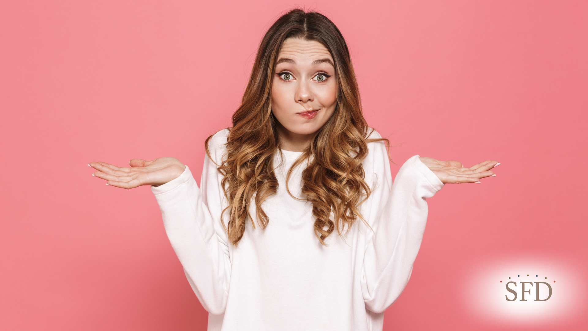 A woman in a white sweater is shrugging her shoulders on a pink background.