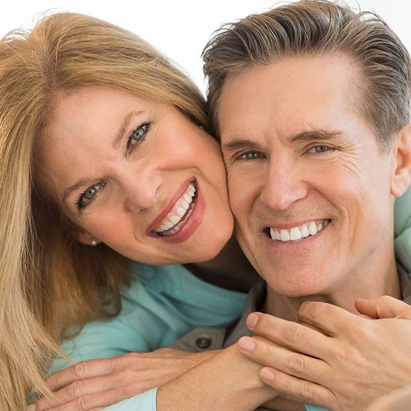 A man and a woman are hugging and smiling for the camera
