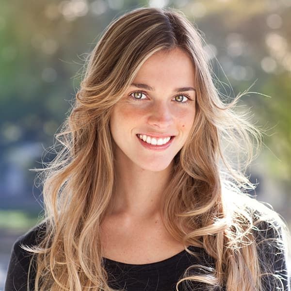 A woman with long blonde hair is smiling and wearing a black shirt.