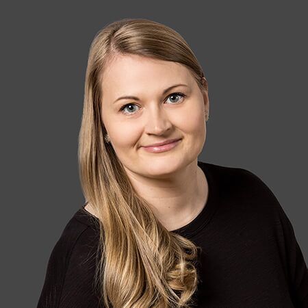 A woman with long blonde hair is wearing a black shirt and smiling for the camera.