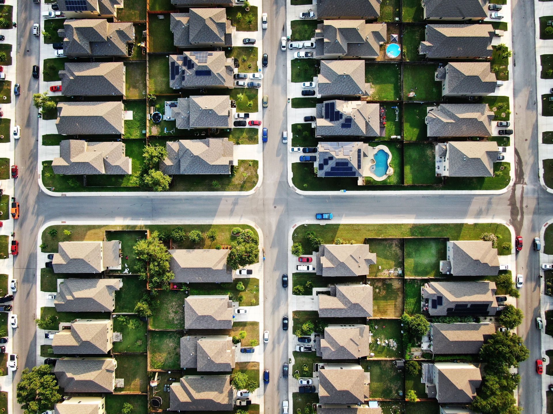 An aerial view of a residential neighborhood with a pool in the middle