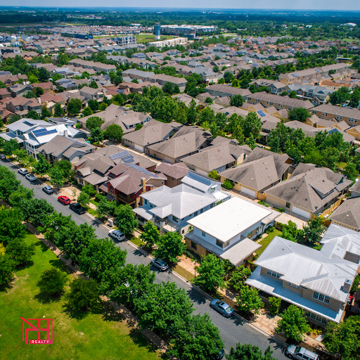 Aerial view of a residential neighborhood, showcasing rows of homes with green lawns and shaded streets.