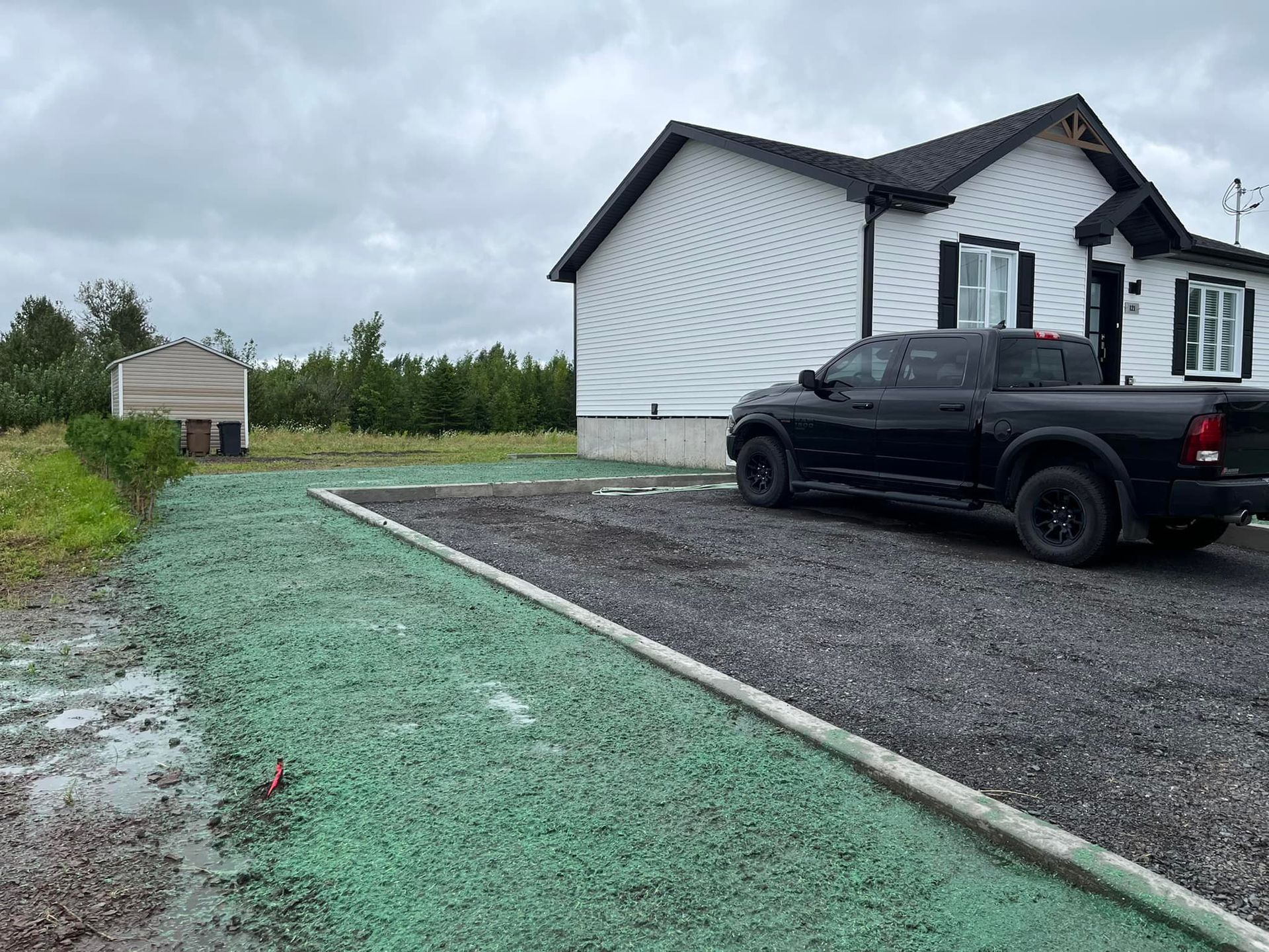 Un camion noir est garé devant une maison blanche.