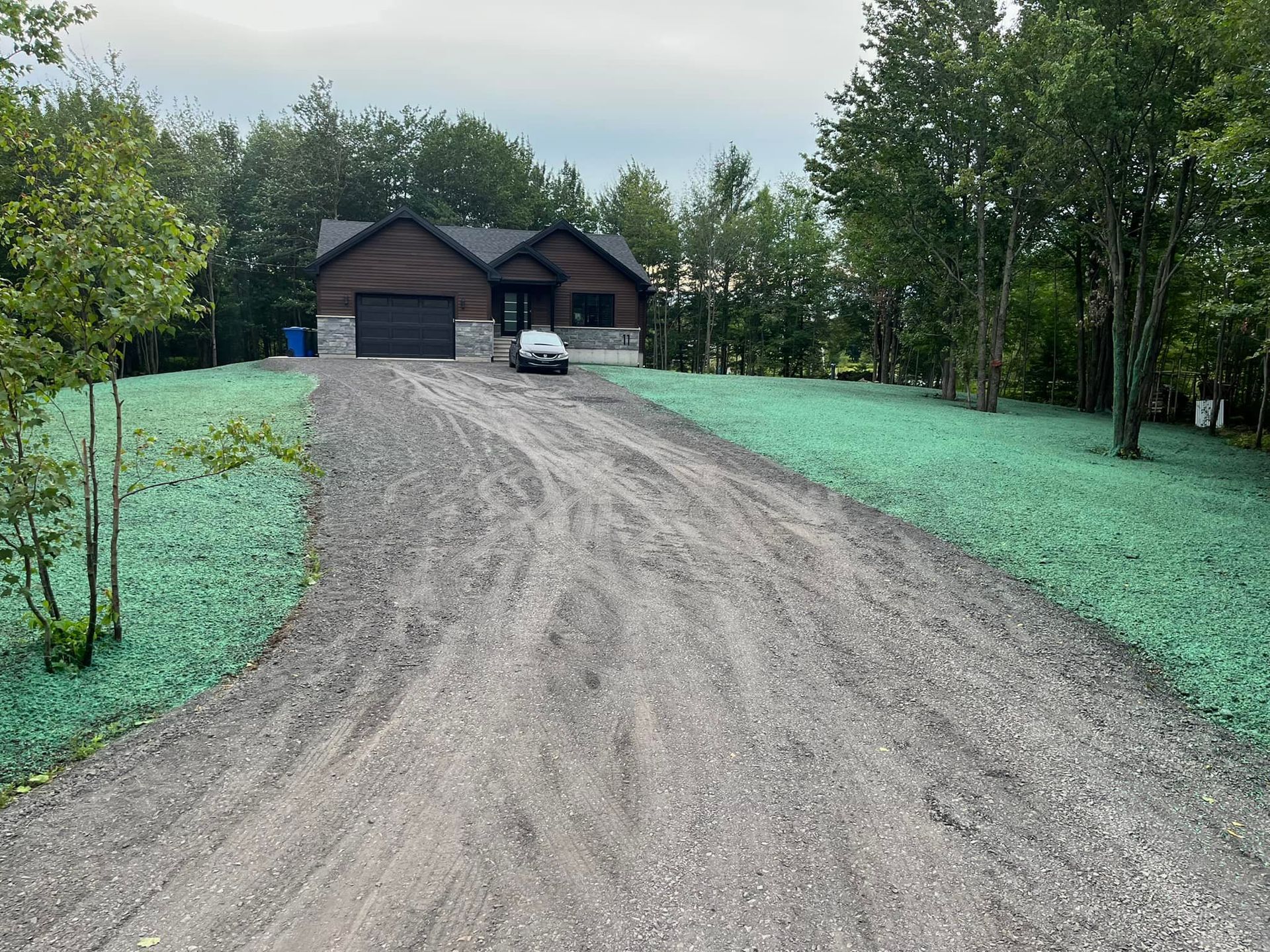 Une voiture roule sur un chemin de terre en direction d'une maison.