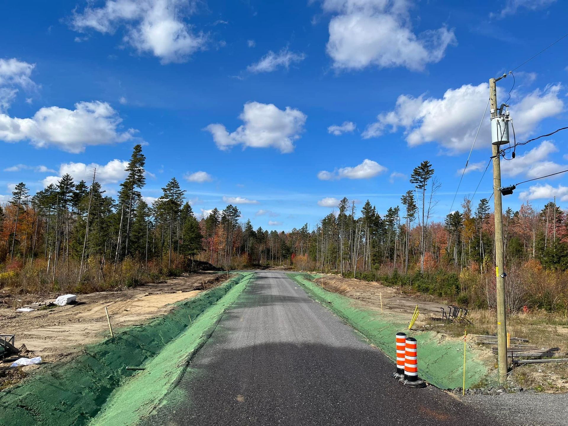 Une route avec des arbres sur le côté et un ciel bleu en arrière-plan.