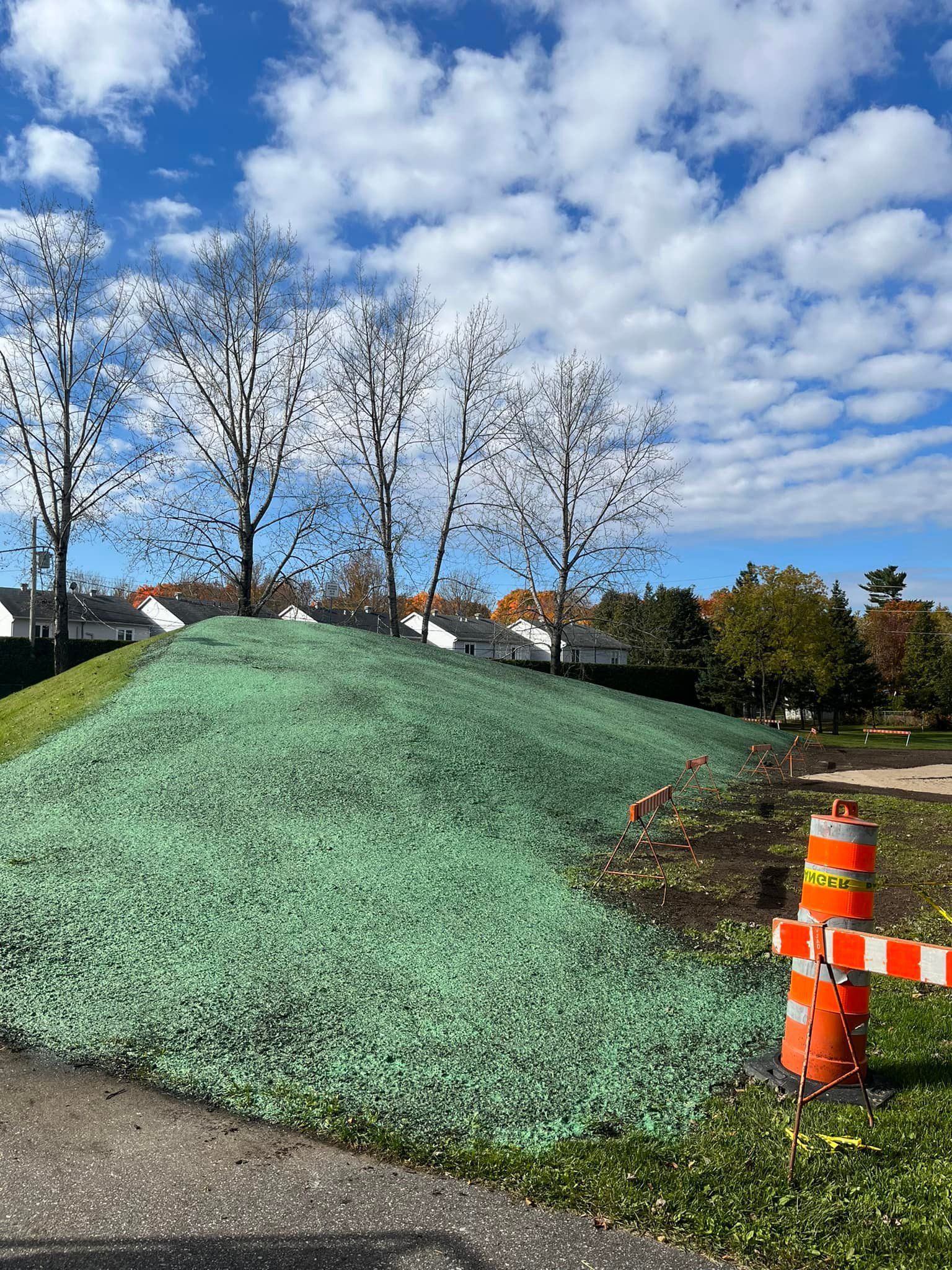 Une bouche d'incendie est placée sur le bord d'une route à côté d'une colline herbeuse.