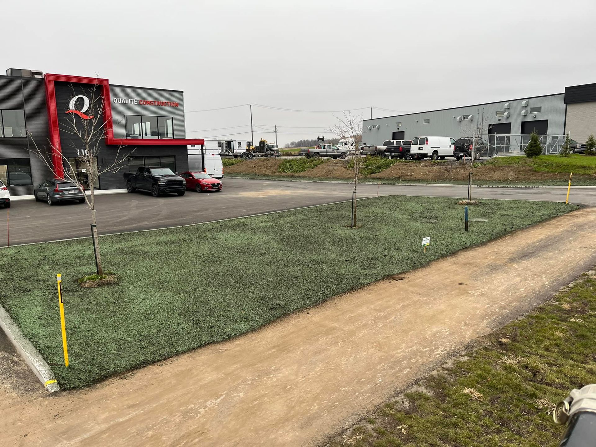 Un chemin de terre menant à un bâtiment avec des voitures garées devant.