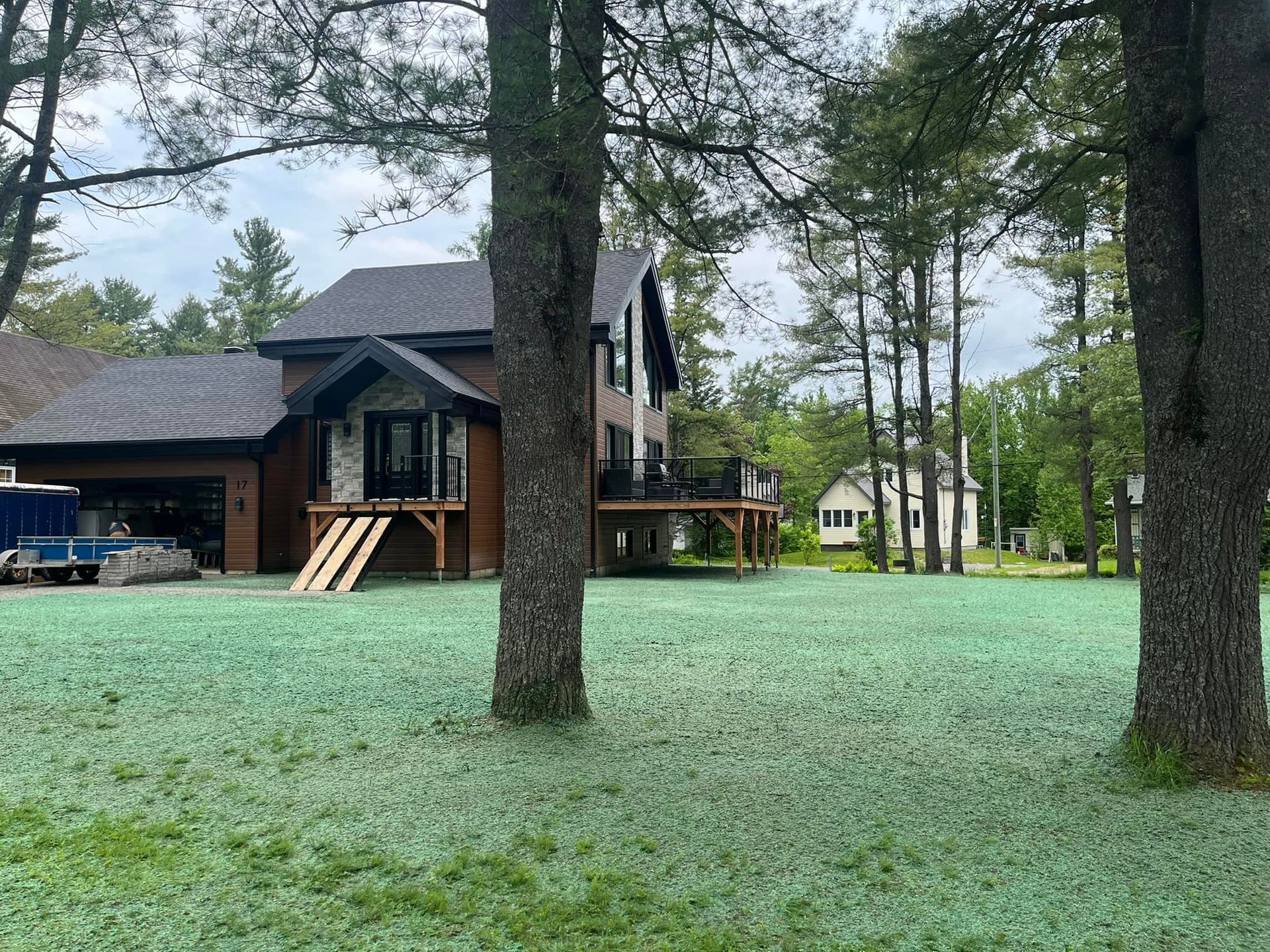 Une grande maison est située au milieu d'un champ verdoyant entouré d'arbres.