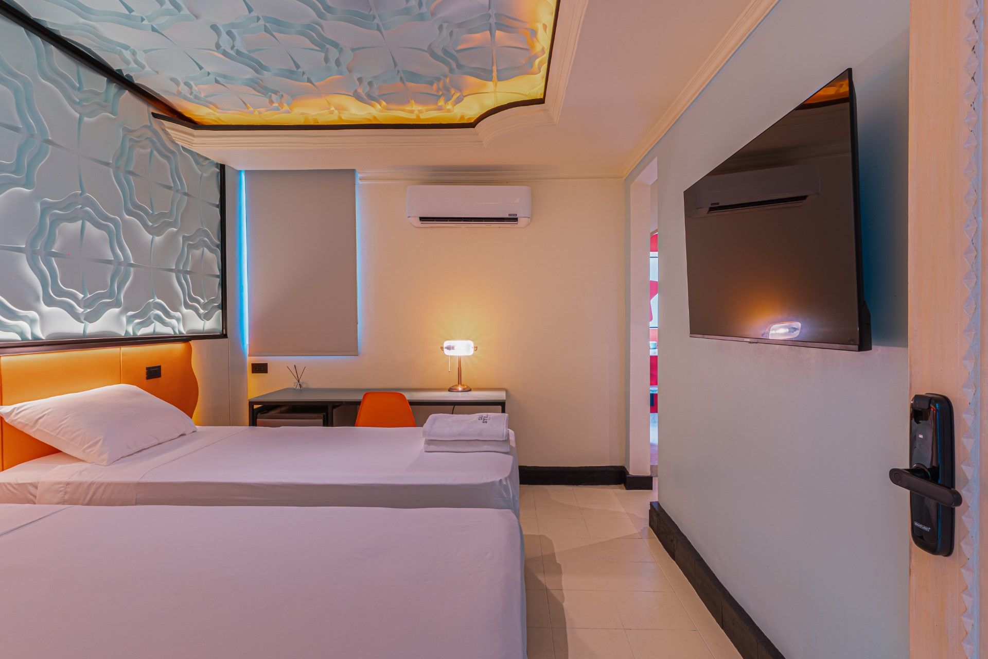 Una habitación de hotel con dos camas, un escritorio, un televisor y un techo decorativo.