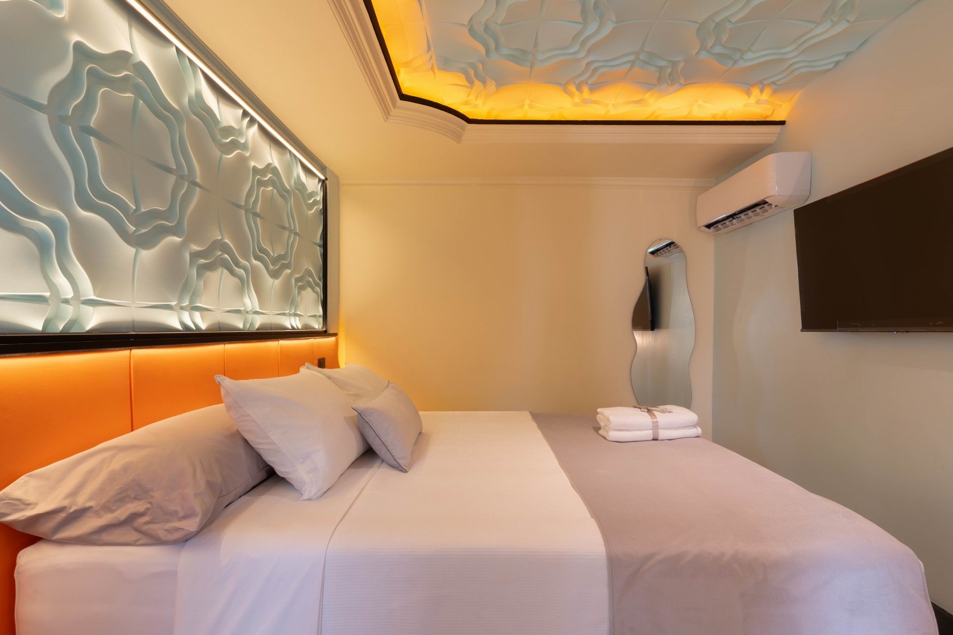 Dormitorio con cama, TV, aire acondicionado y diseño de panel decorativo de pared y techo.