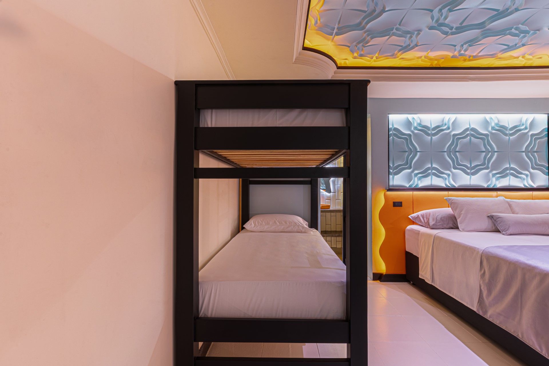 Litera negra en una habitación con una cama blanca, decoración de pared estampada e iluminación de acento naranja.