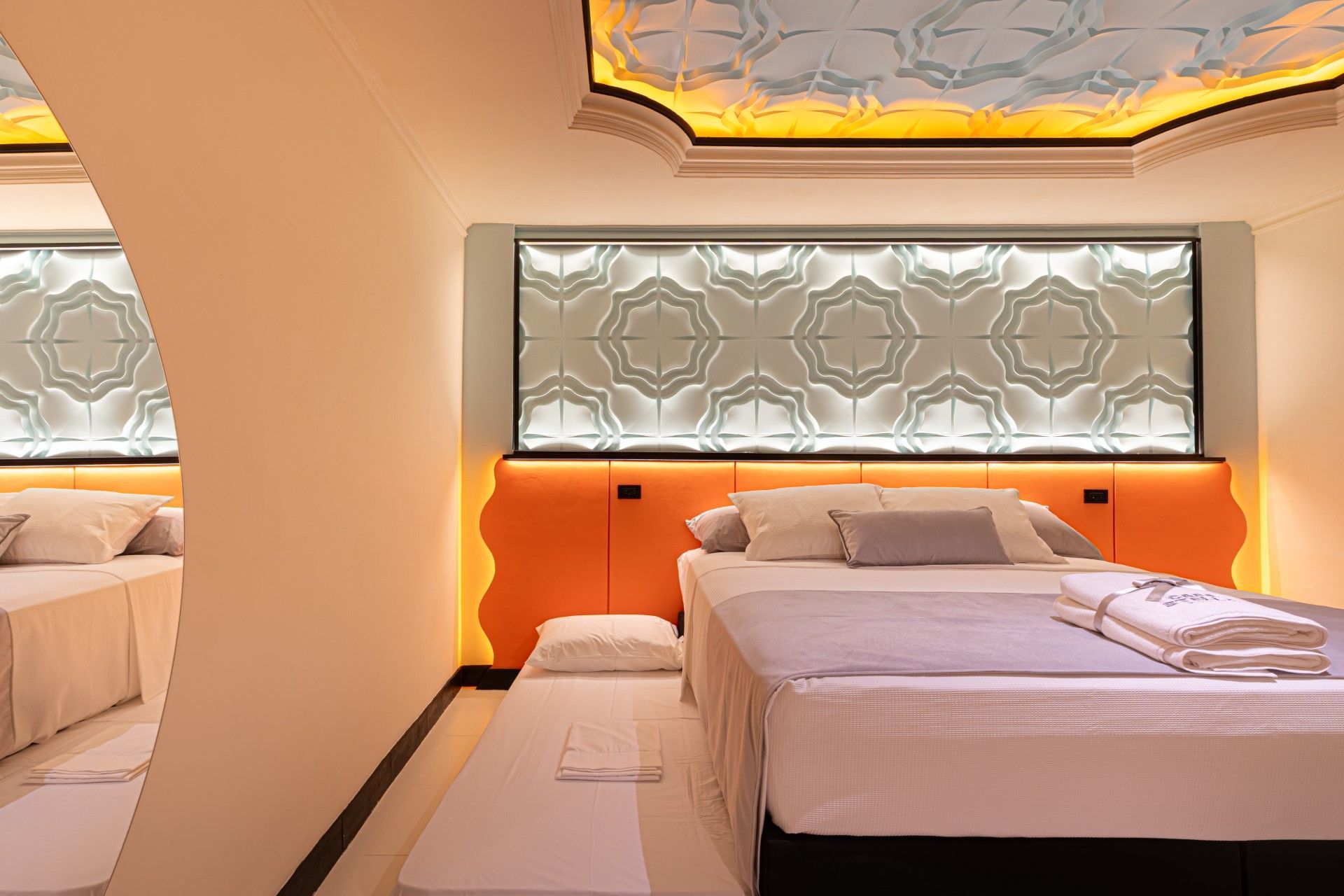 Dormitorio con cama doble, cama individual adicional y detalles ornamentados en el techo.