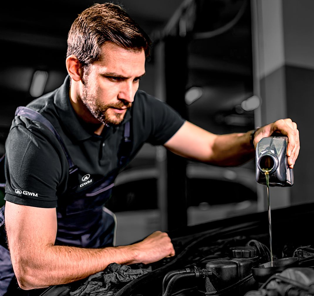 Mecánico vertiendo aceite en el motor de un coche en un garaje.