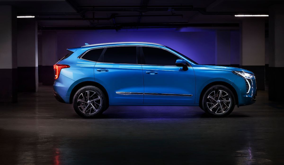 SUV azul estacionado en un garaje oscuro con un fondo de luz azul.