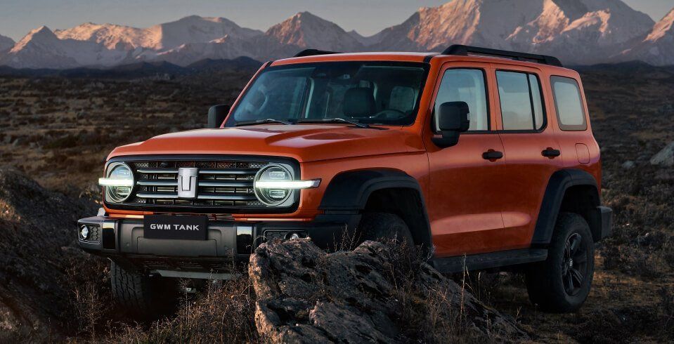 Todoterreno todoterreno de color naranja en un paisaje rocoso con montañas al fondo.