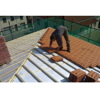 operaio posa tegole color mattone sul tetto