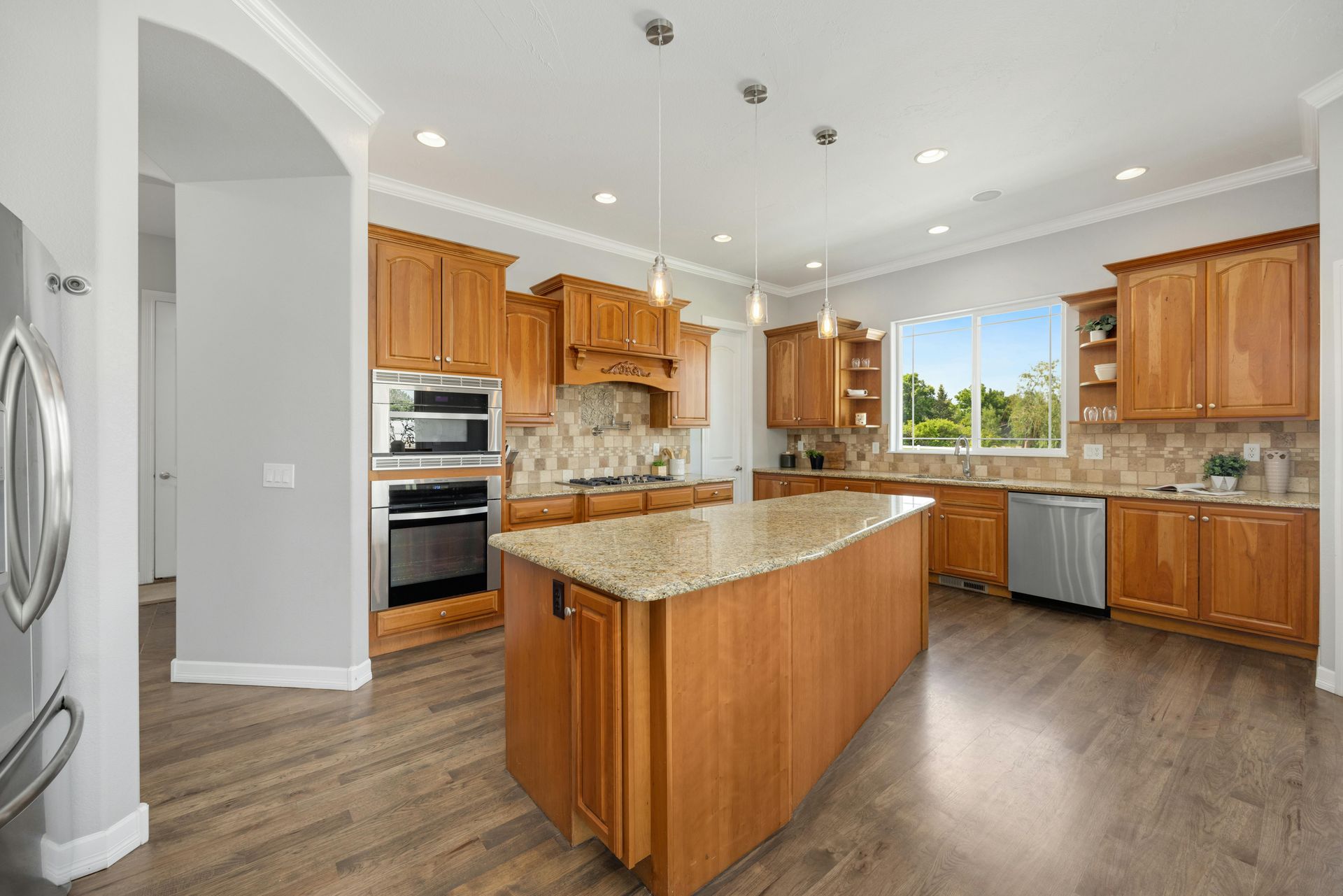 Spacious kitchen with wood cabinets, island, granite countertops, and stainless steel appliances.