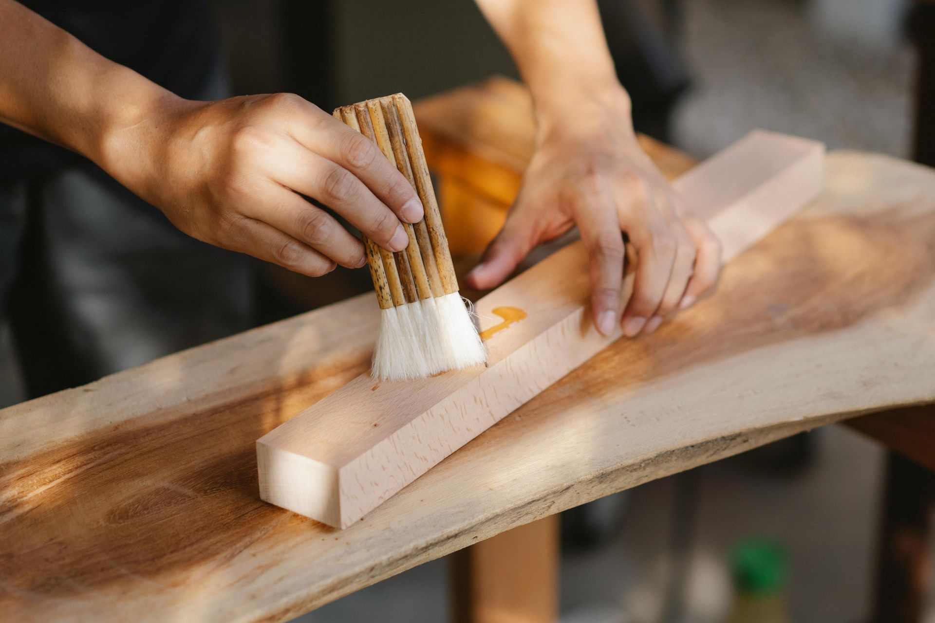 Person applying glue to a wooden plank with a brush.