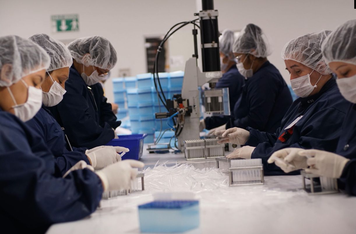 A group of people wearing masks and gowns are working in a lab