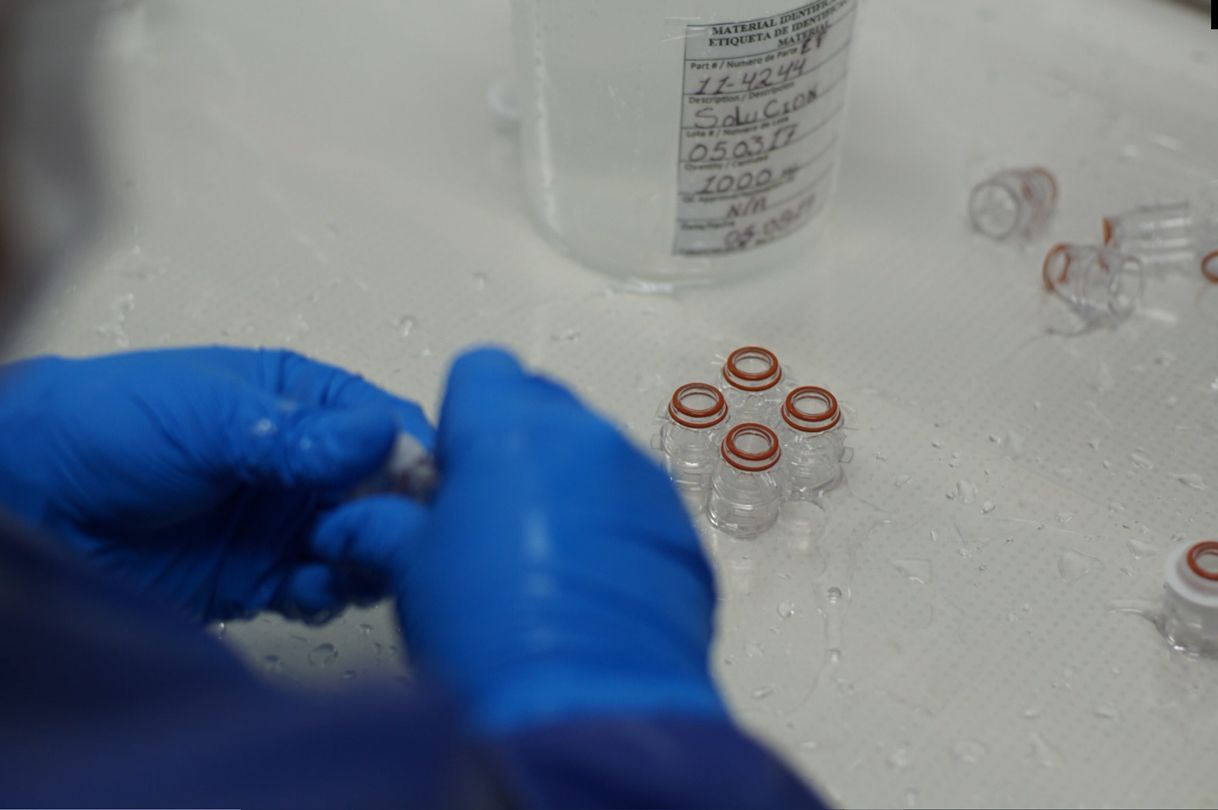 A person wearing blue gloves is cleaning a bottle in a laboratory