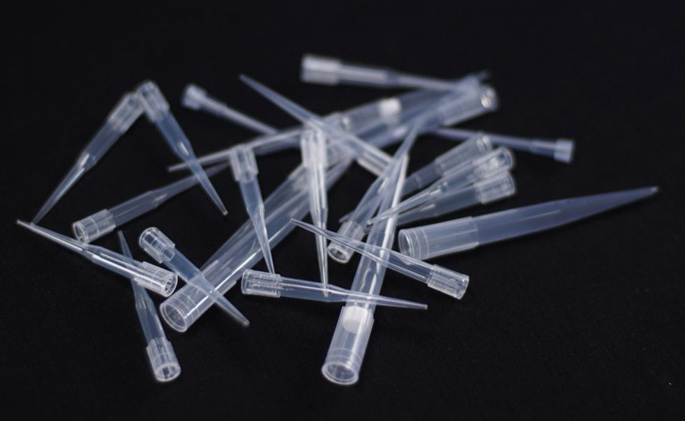 A pile of plastic pipettes on a black surface