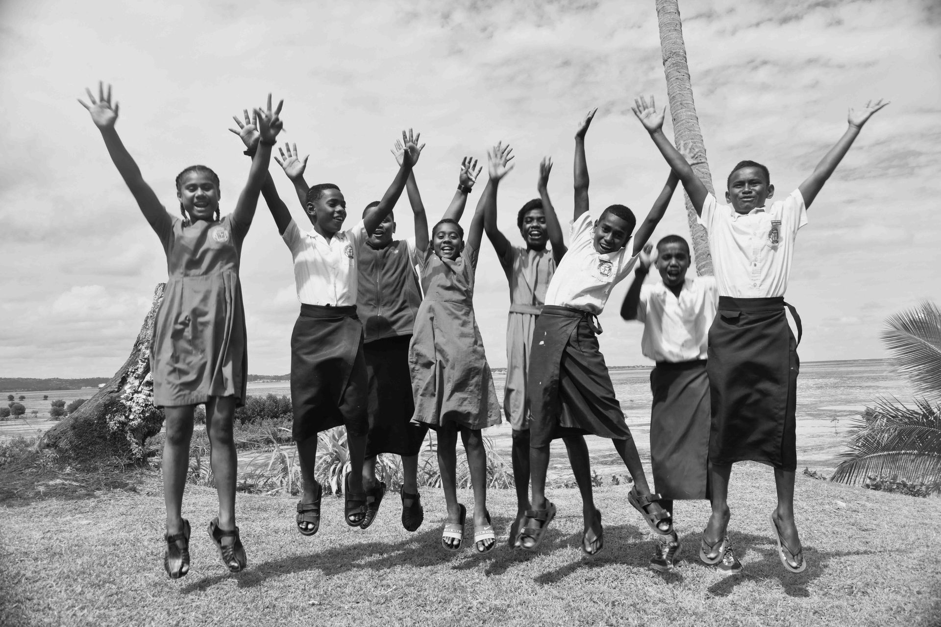 Fijian school children jumping in the air laughing and smiling