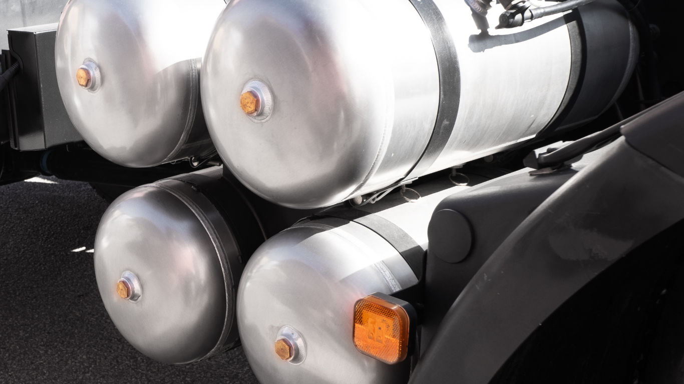 Four cylindrical air tanks mounted on a black vehicle frame, with amber lights.