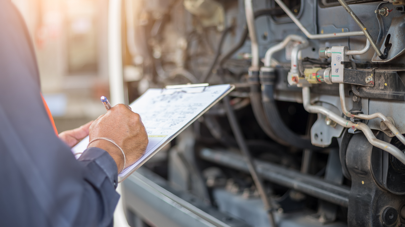 Mechanic examining a vehicle engine with clipboard in hand.