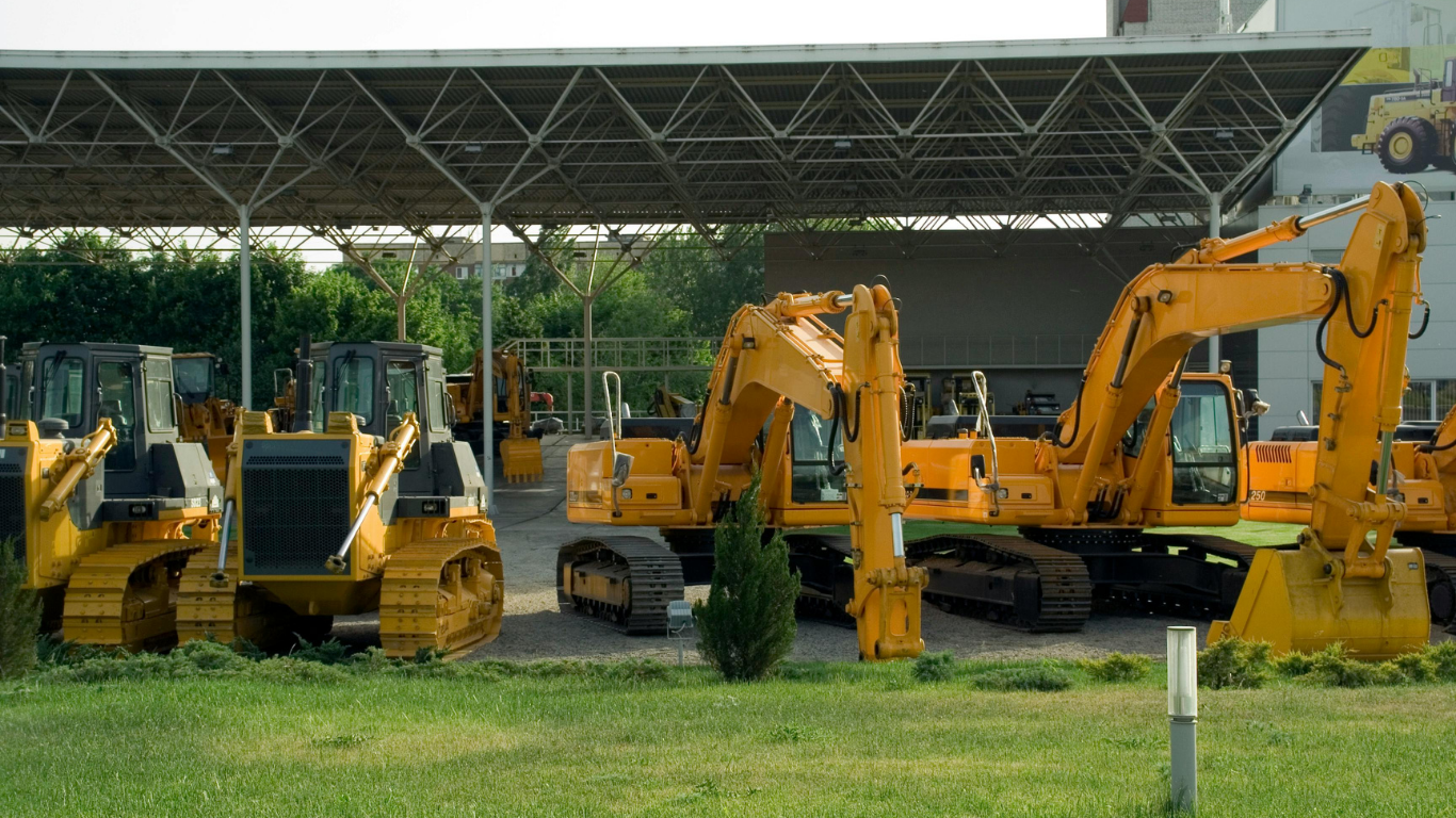Yellow construction equipment parked in front of a building, including bulldozers and excavators.