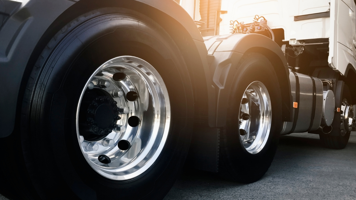 Close-up of a semi-truck's shiny tires and rims. Sunlight is shining.