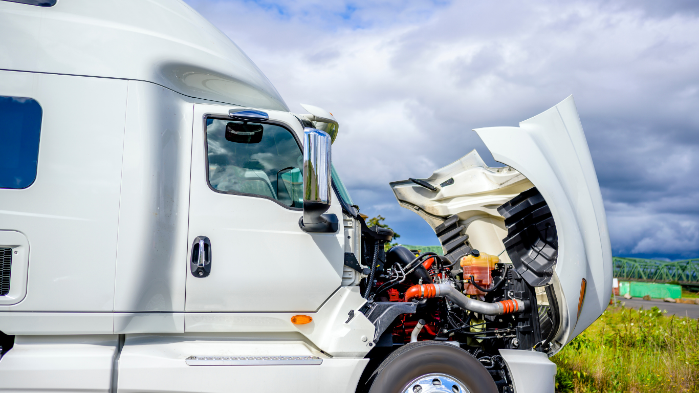 White semi-truck with open hood; engine visible, roadside setting.