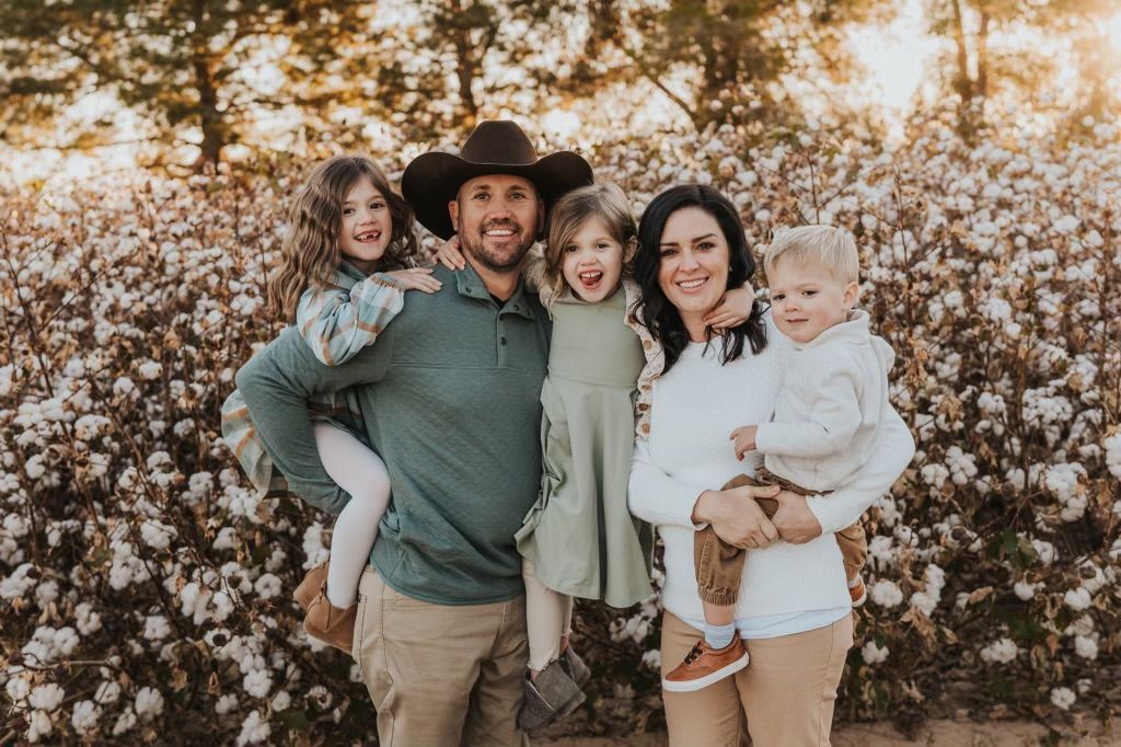 a family is posing for a picture in a field of cotton .