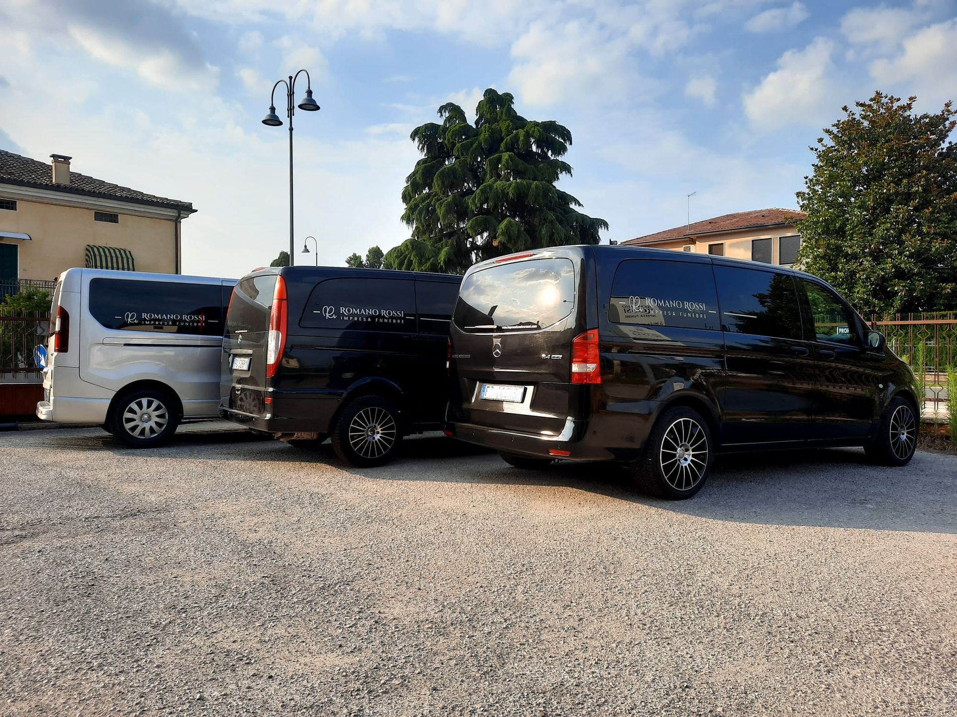 Due furgoni funebri sono parcheggiati uno accanto all'altro in uno spiazzo ghiaioso.