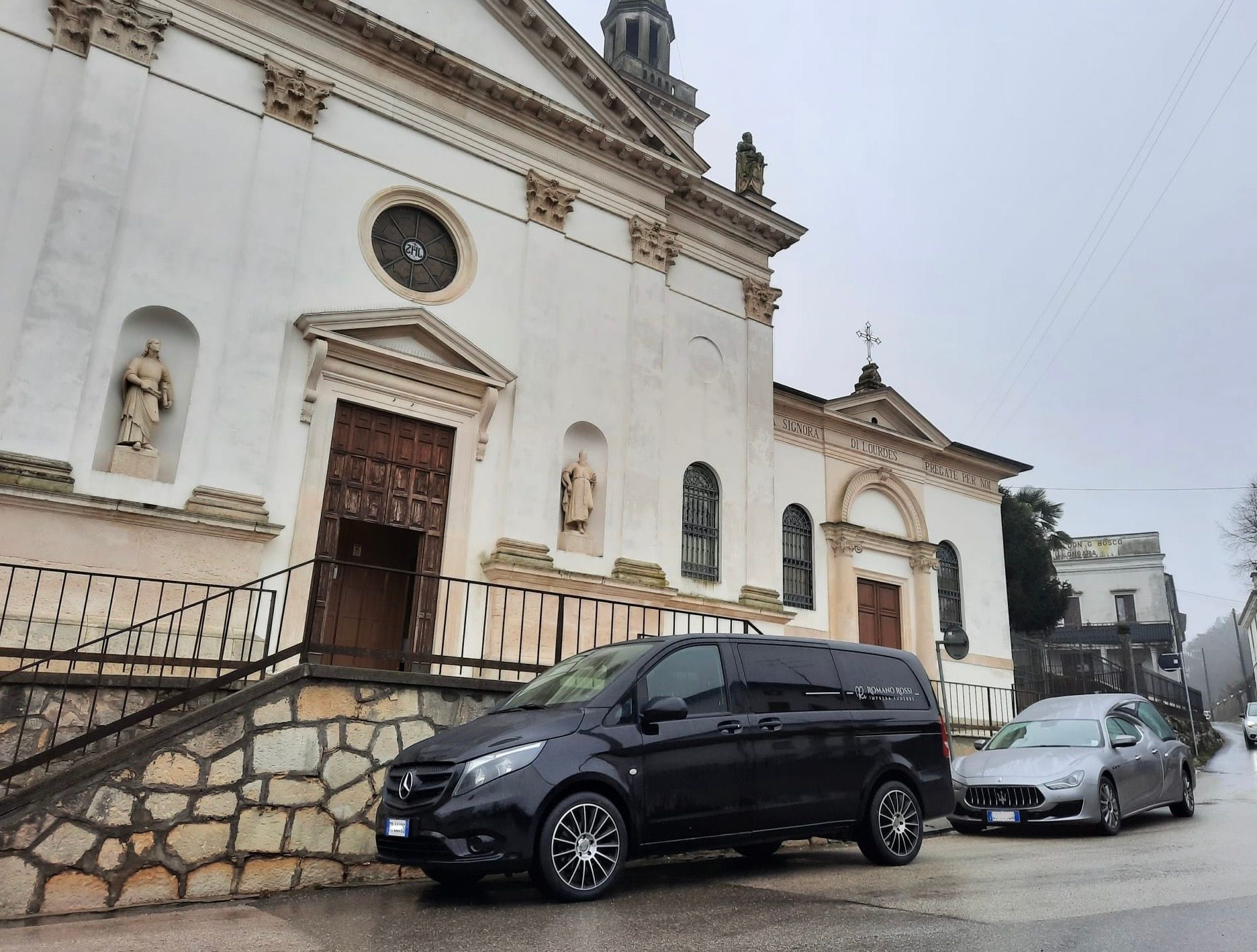 Un carro funebre è parcheggiato davanti a una chiesa.