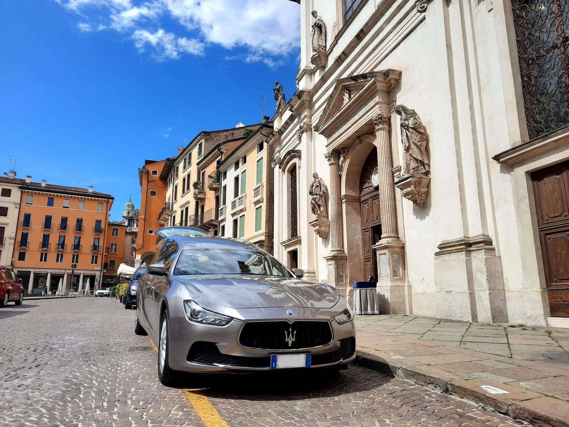 Una maserati per trasporto funebre è parcheggiata sul ciglio della strada davanti a un edificio.